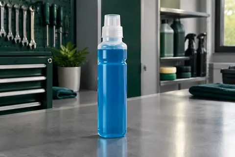 Flacon compact de lave-glace concentré bleu posé sur un établi gris dans un atelier automobile propre.